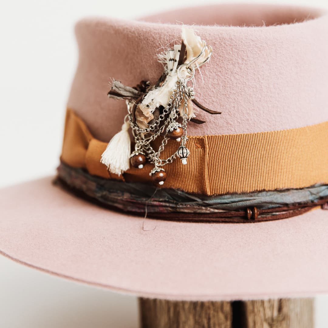 Close up of chunky hat pin with tassel, silver chains, charms and wooden beads on The Blush hat by PHYLLi Designs.