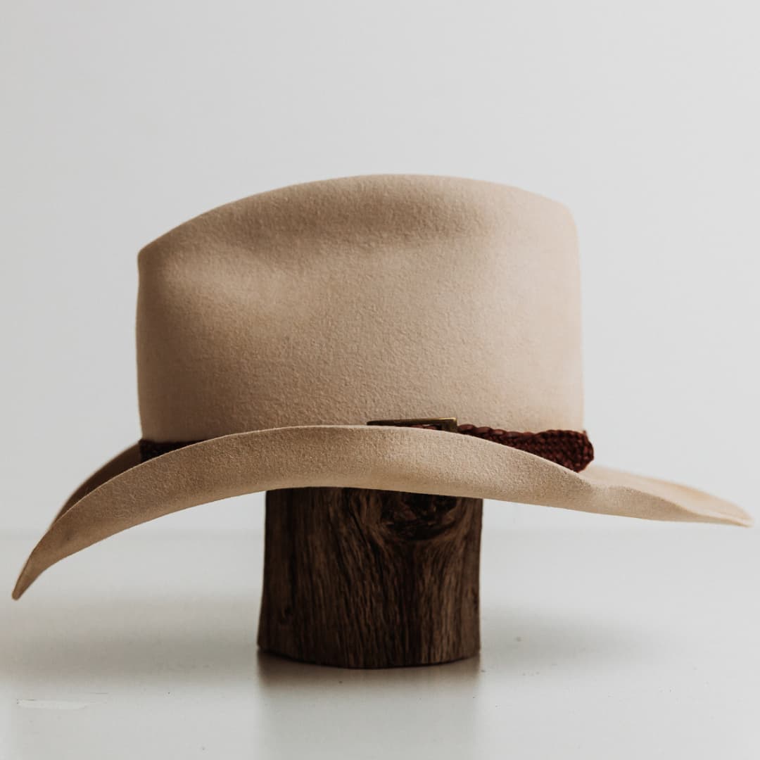 Left side view of The Contractor premium felt hat in Beige with 12 strand plaited leather hat band in Chocolate featuring bronze buckle.