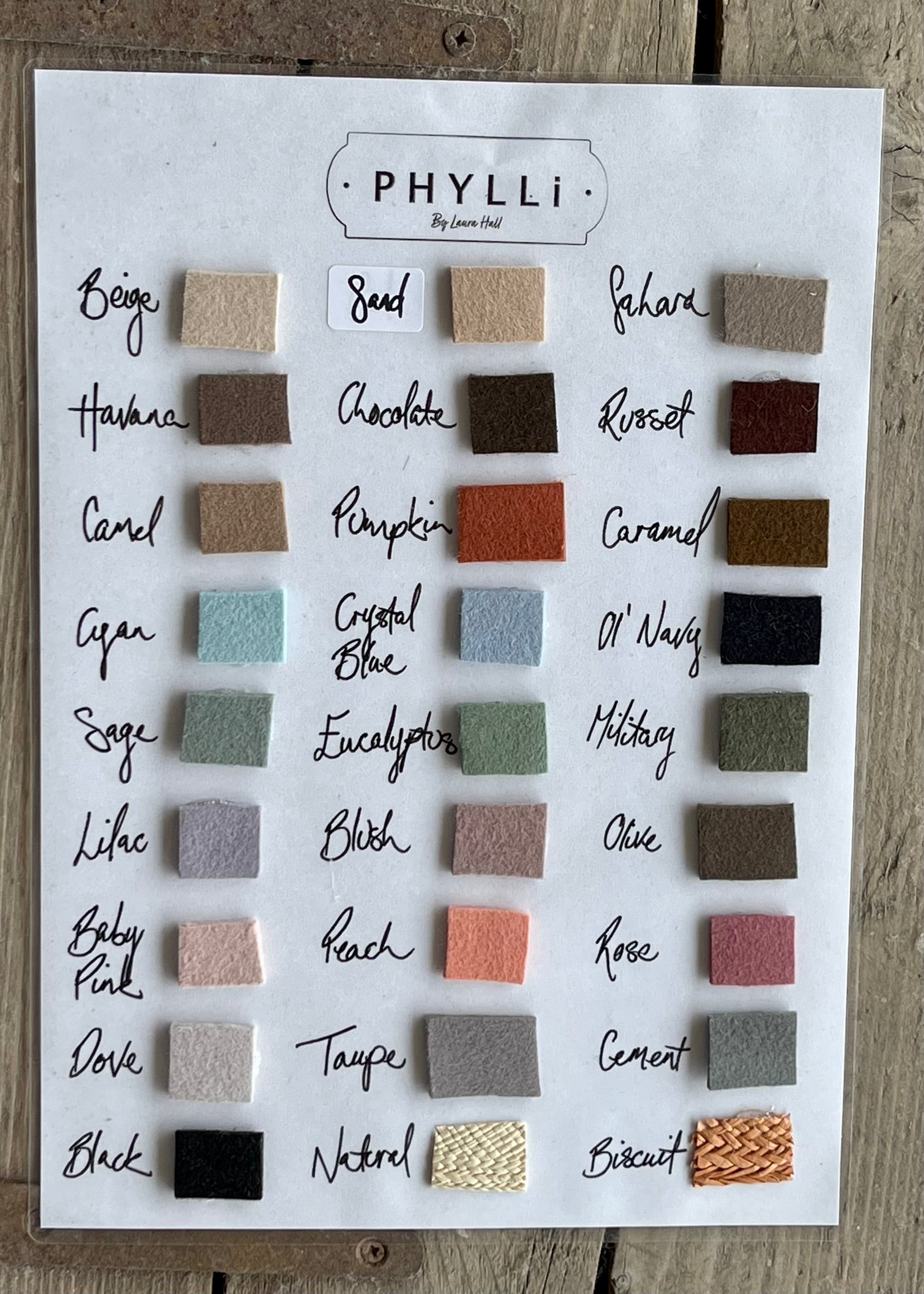 Custom hat colour swatch chart by PHYLLi Designs displayed on a timber surface.
