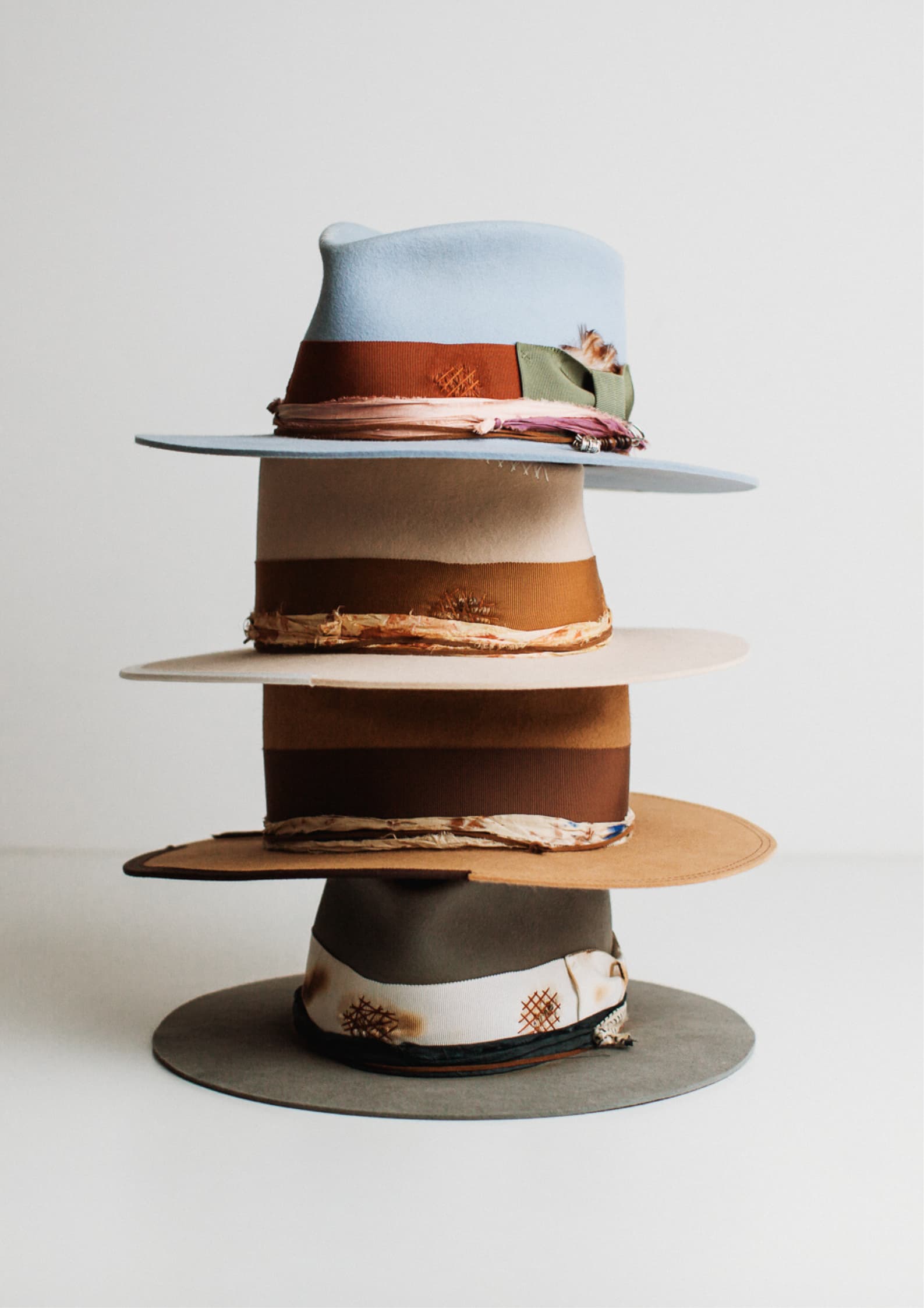 Stack of colourful PHYLLi Designs felt hats on a white background.