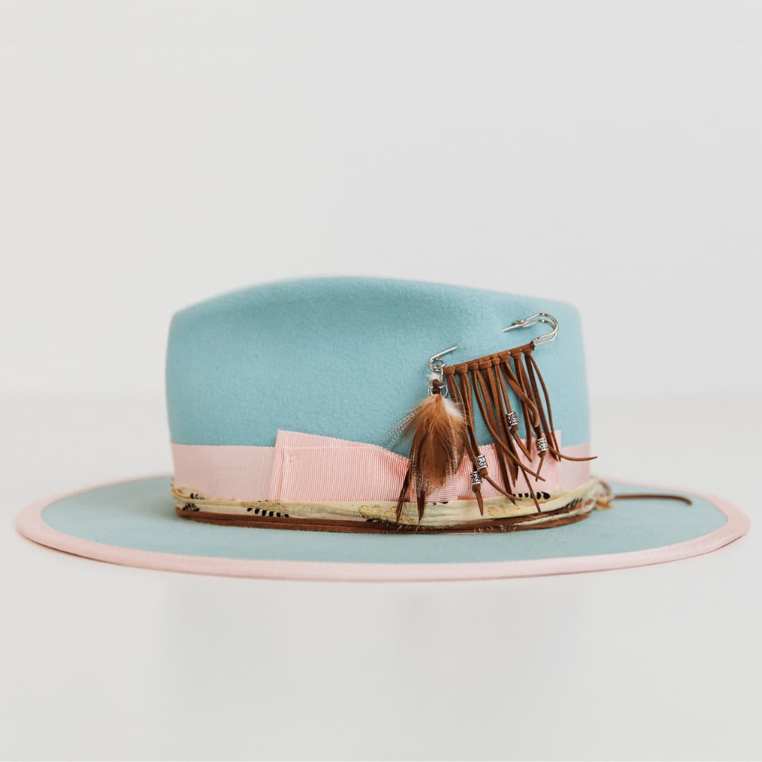 Left side view of The Cyan felt hat by PHYLLi Designs with cream and black sari silk trimming and tan suede string.