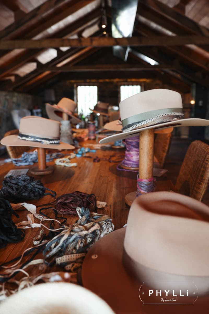 Hat styling table setup with felt hats, ribbons and trims during a private PHYLLi Group Hat Party.
