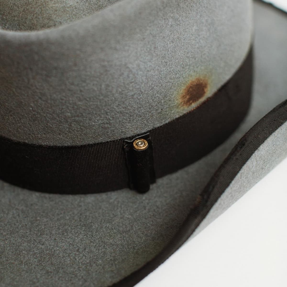 Close-up detail of Hornet charcoal felt cowboy hat showing black grosgrain band and bullet casing accent.