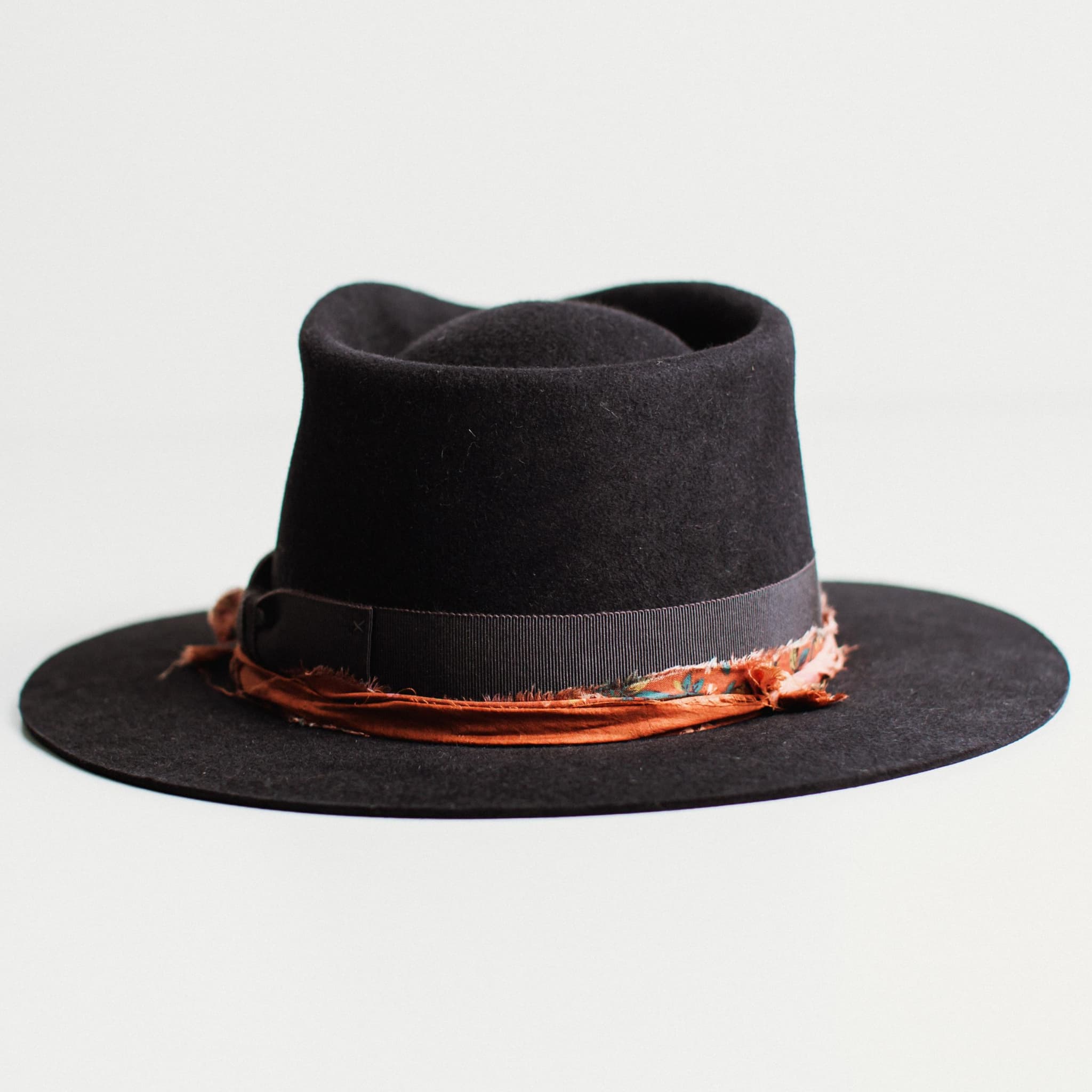 Back view of dark navy felt hat with decorative band by PHYLLi Designs on a light grey background.