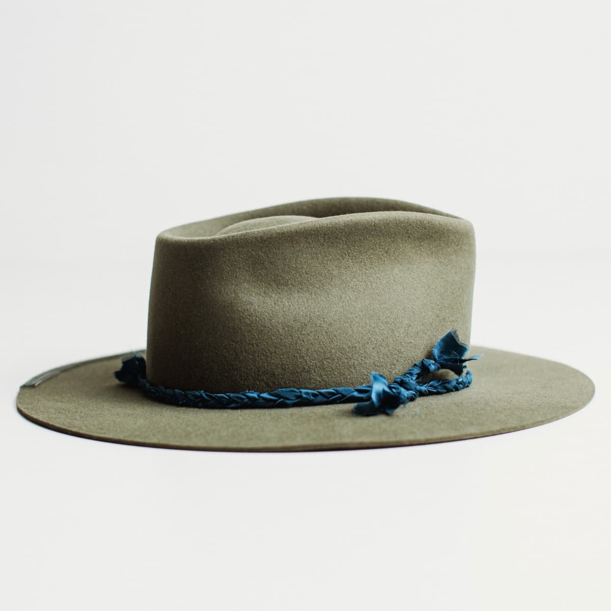 Right side view of military felt hat with silk plait band and floating bow detail.