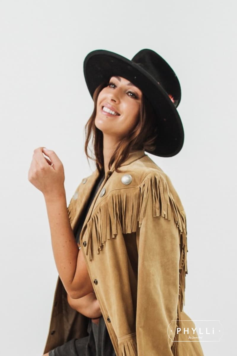 Woman wearing a black felt hat by PHYLLi Designs styled with a tan fringe jacket on a white background.