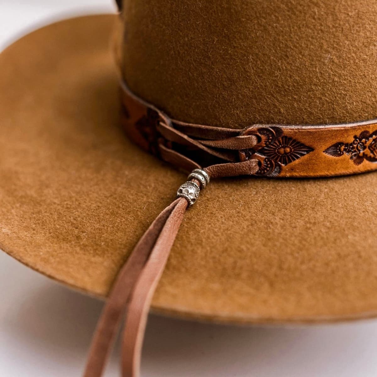 Close up detail of the The PHYLLi Caramel cowboy hat showing leather tie back band with metal bead finishing.