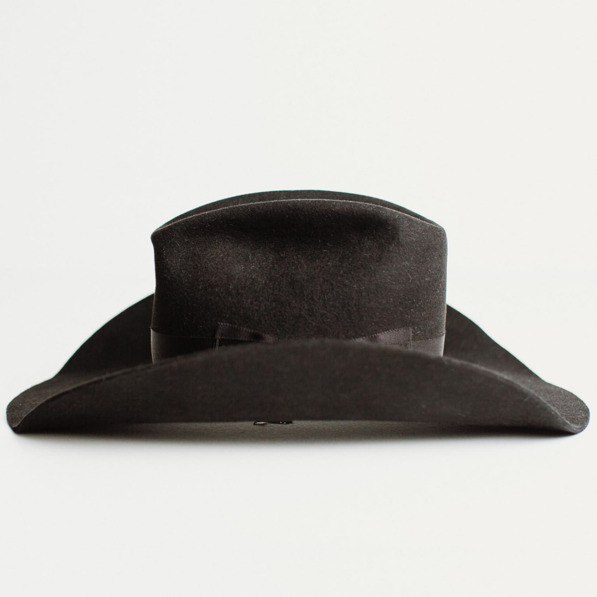 Left side view of The Plains black felt cowboy hat by PHYLLi Designs with wide shaped brim and grosgrain bow band.