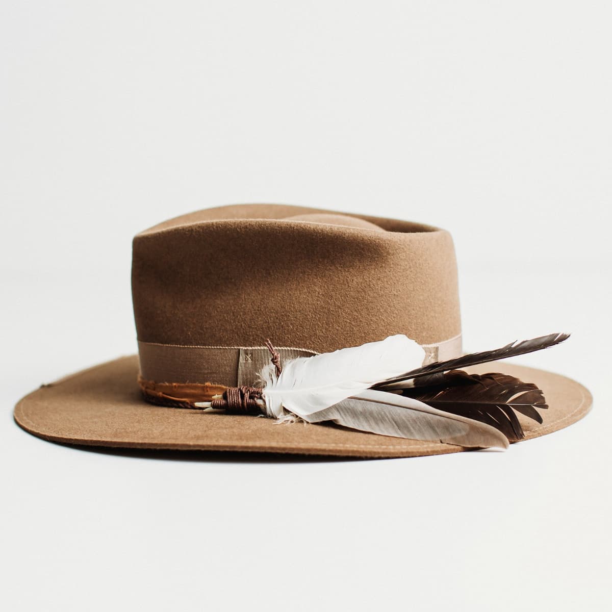Left side view of havana brown felt hat with vintage grosgrain bow band, distressed brim trim and feather accent by PHYLLi Designs.