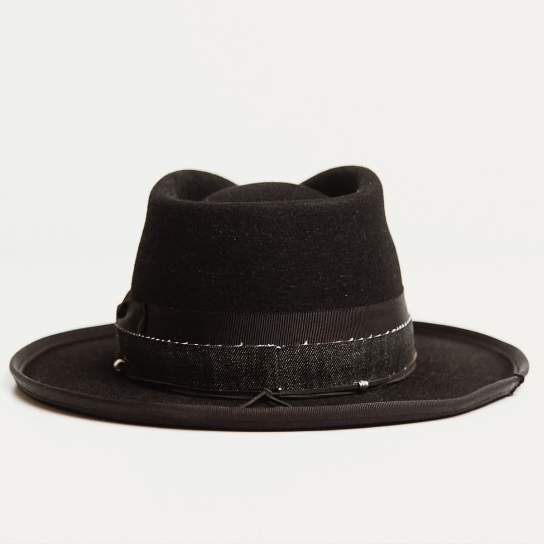 Back view of black felt hat with decorative band and pencil curl brim on a light grey background.