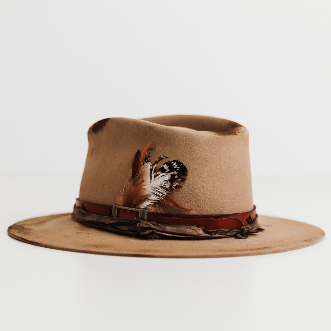 Back left angle of The Safari distressed Sahara felt hat by PHYLLi Designs with antique leather belt band and feather detail.