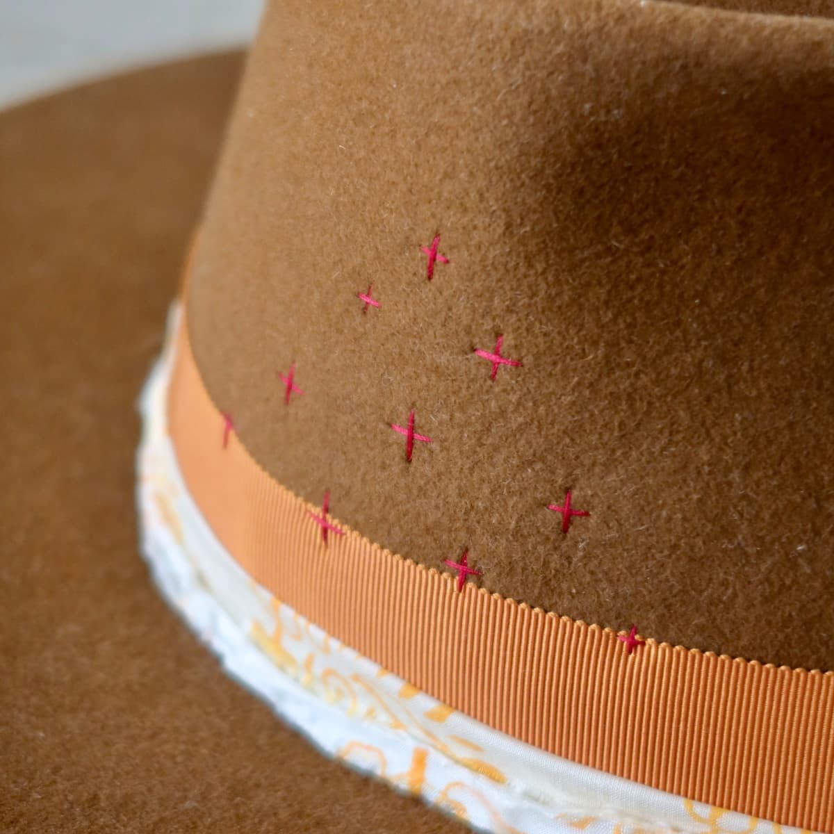 Close-up detail of caramel felt hat showing hand stitched cross pattern on crown by PHYLLi Designs.