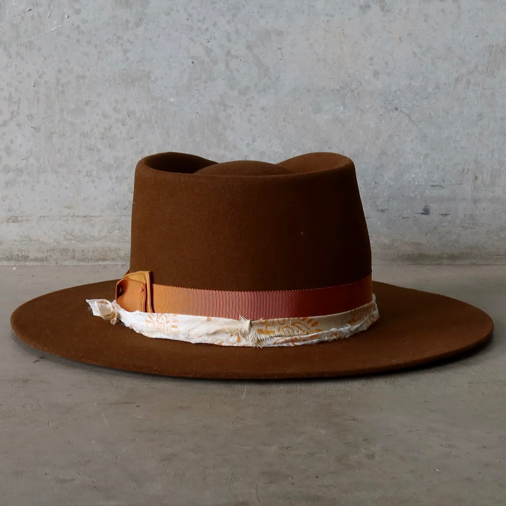Back view of caramel felt hat with grosgrain band and patterned silk trim by PHYLLi Designs.