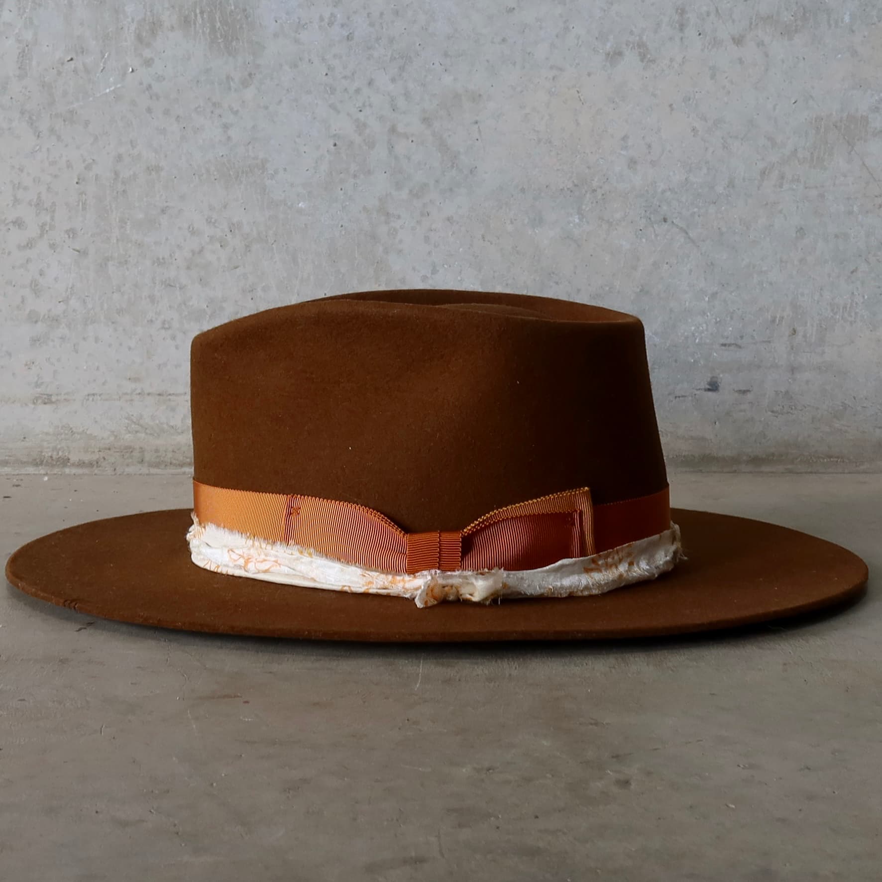 Left side view of caramel felt hat with wide brim and layered trim detail by PHYLLi Designs.