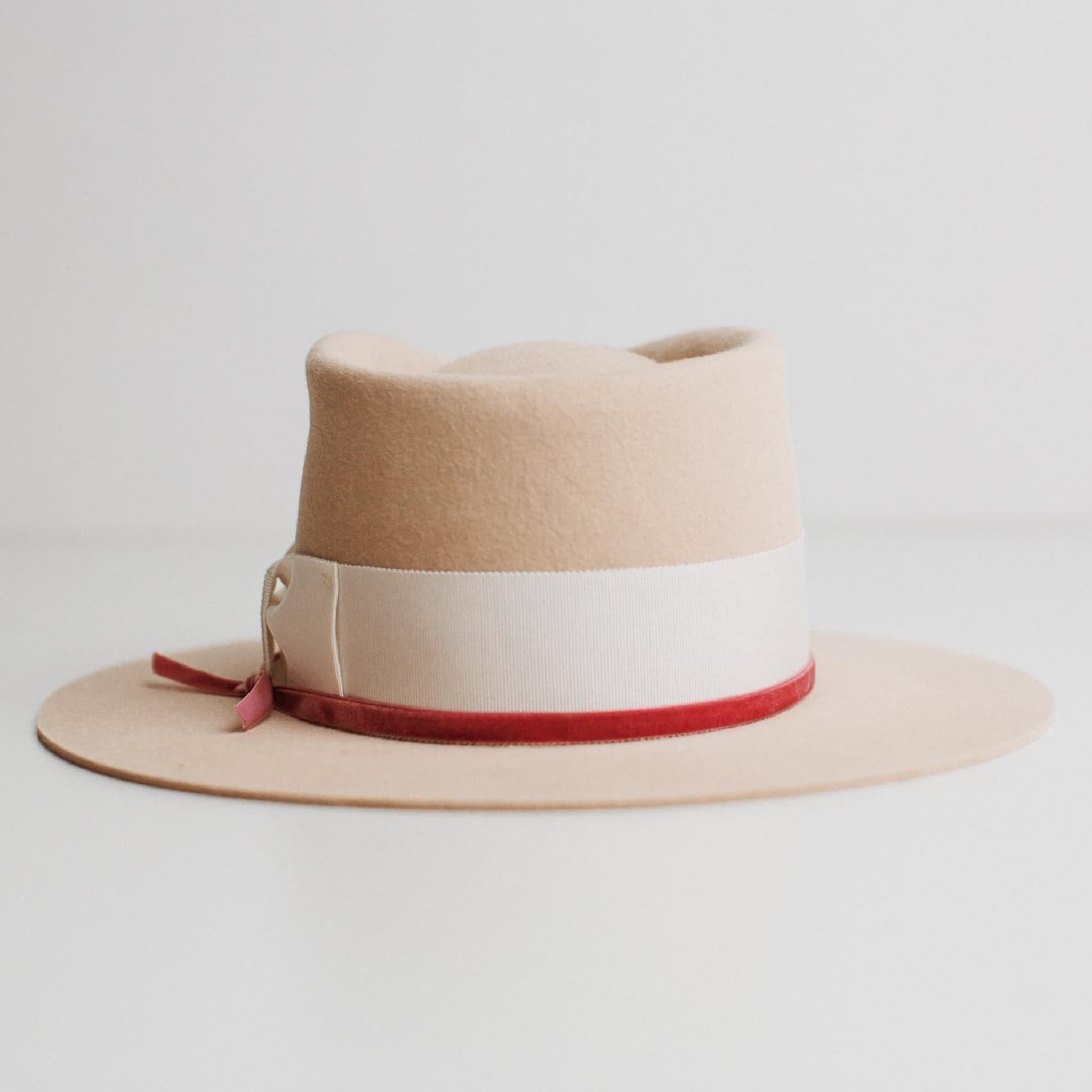 Back view of beige felt hat with ivory band and pink velvet ribbon by PHYLLi Designs on a light grey background.