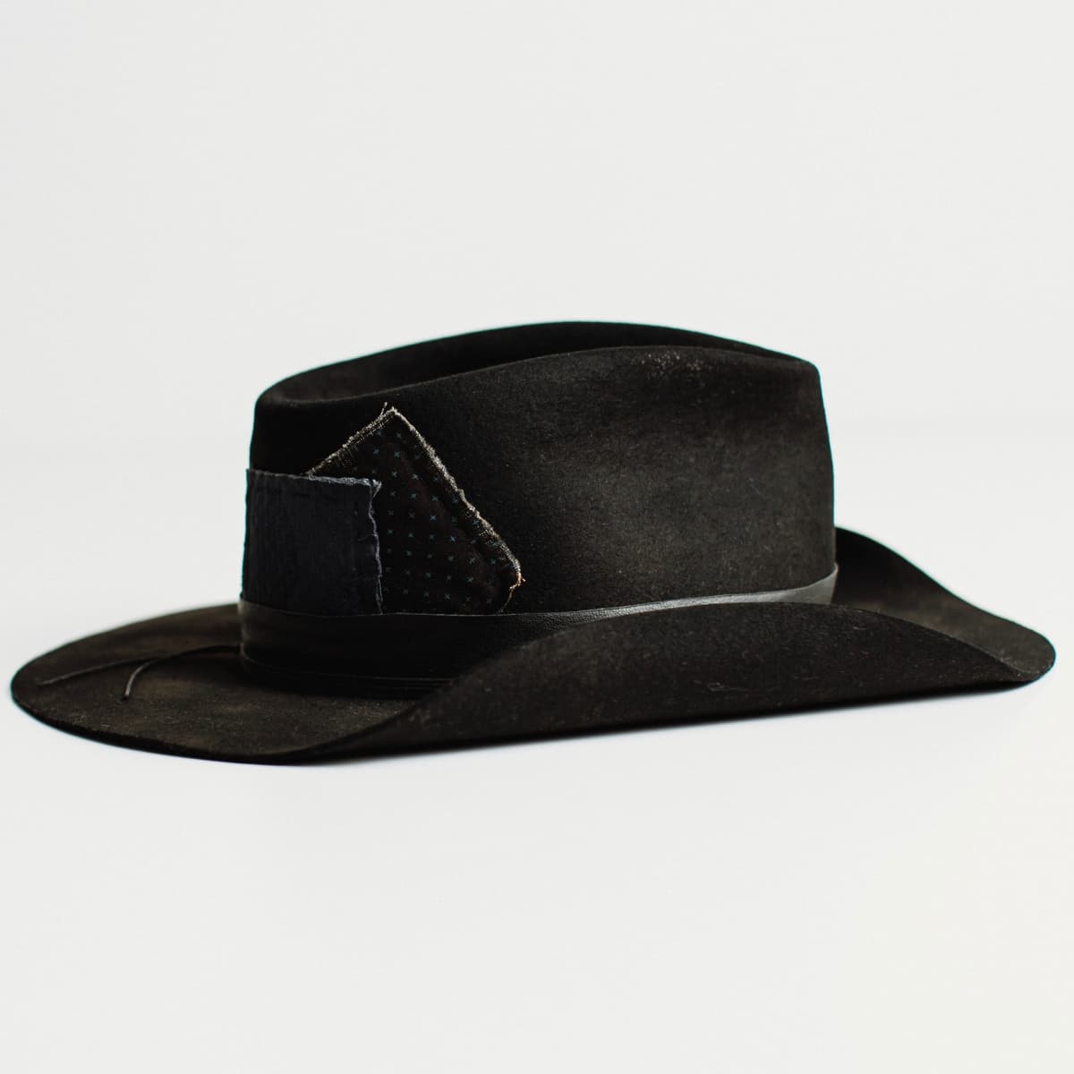 Right side view of black felt cowboy hat by PHYLLi Designs on a white background.