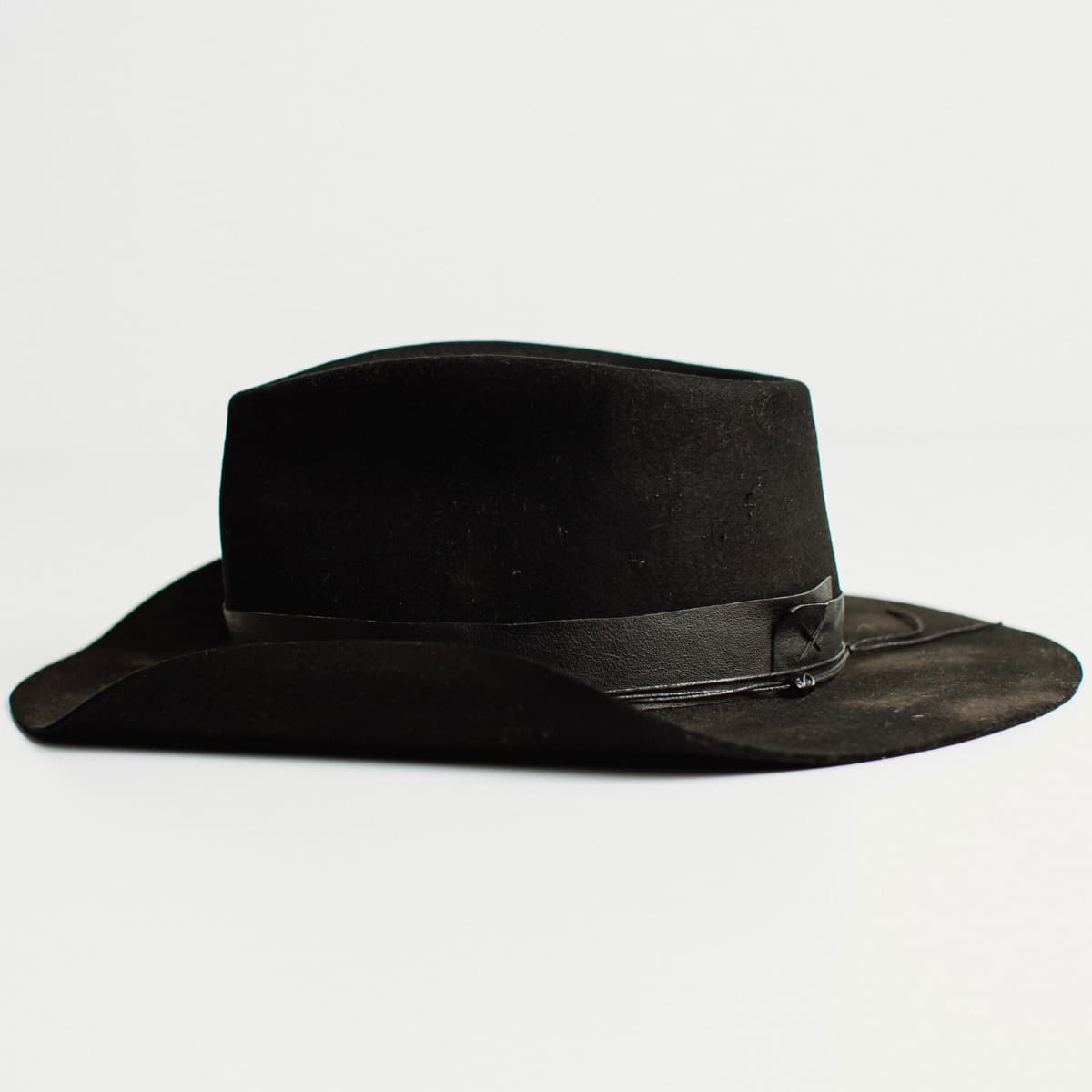 Left side view of black felt cowboy hat by PHYLLi Designs on a white background.