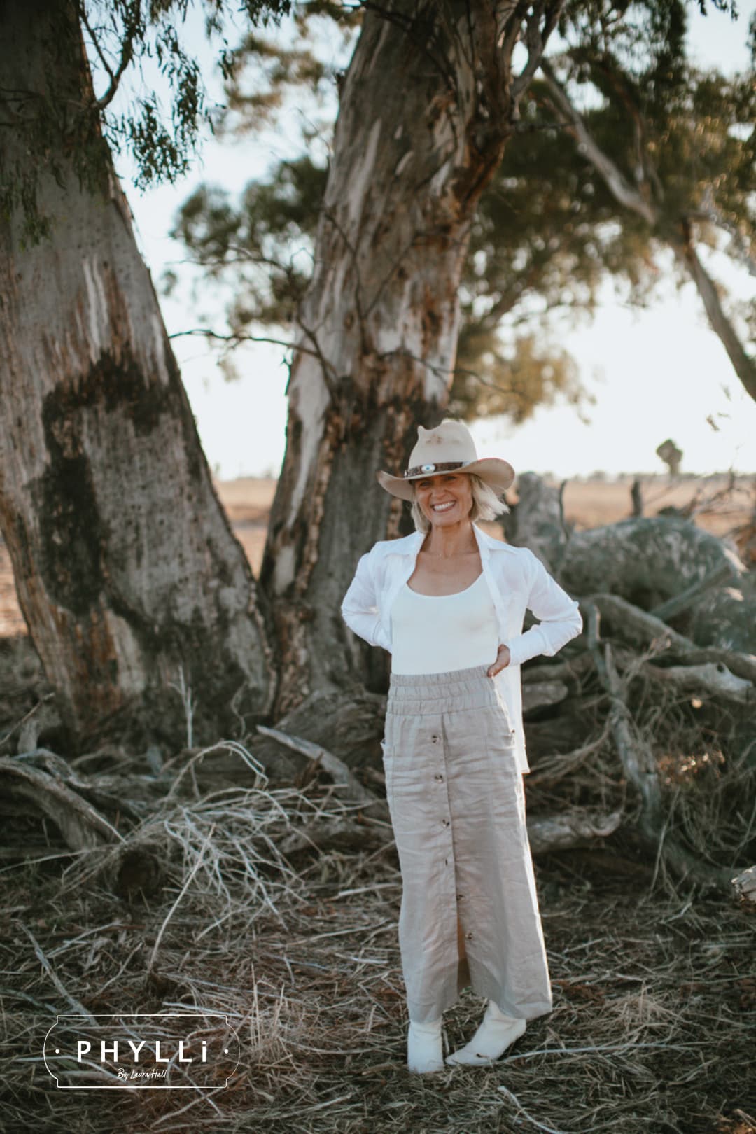 Woman standing in Australian bushland wearing The Wheeler premium felt hat in distressed Beige.