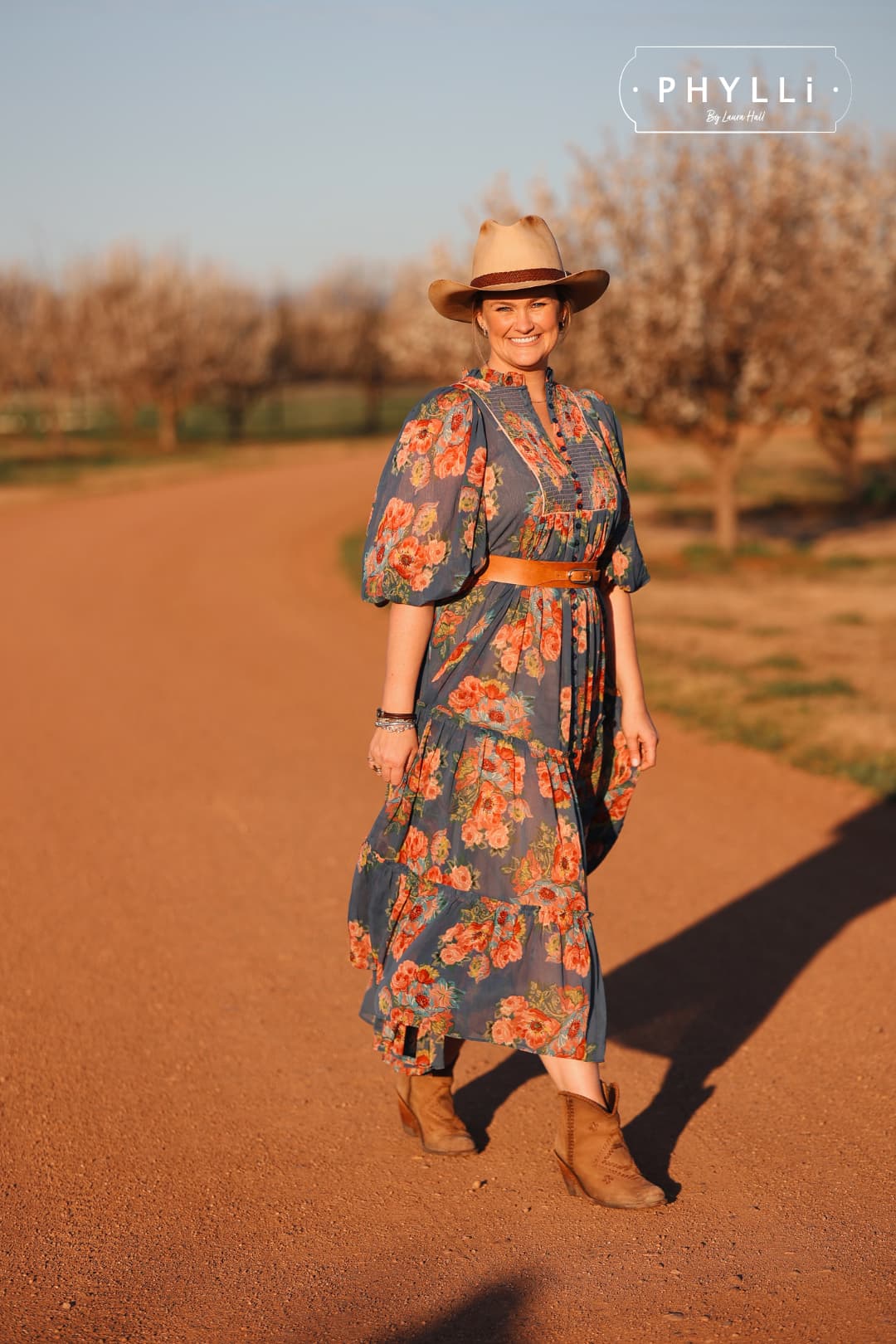 Laura Hall walking through orchard wearing The Wheeler premium felt hat in distressed Beige with 12 strand leather hat band in Chocolate.