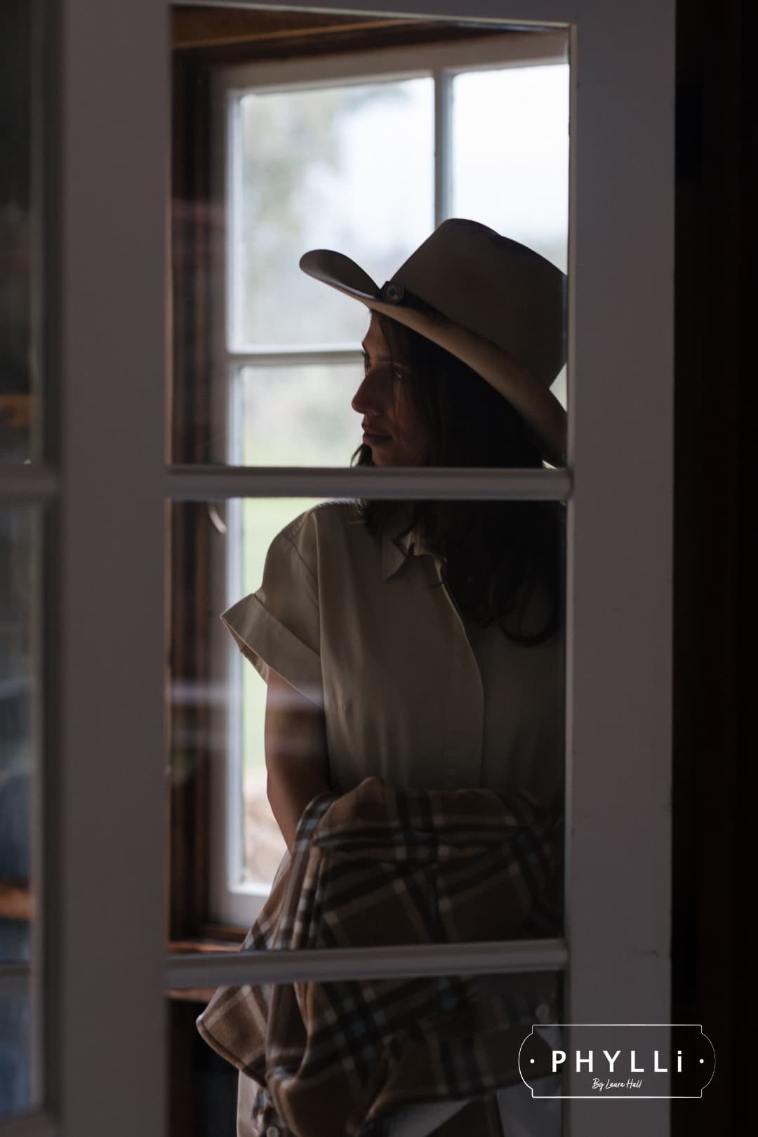 Side profile portrait of woman indoors wearing The Wheeler premium felt hat in distressed Beige.