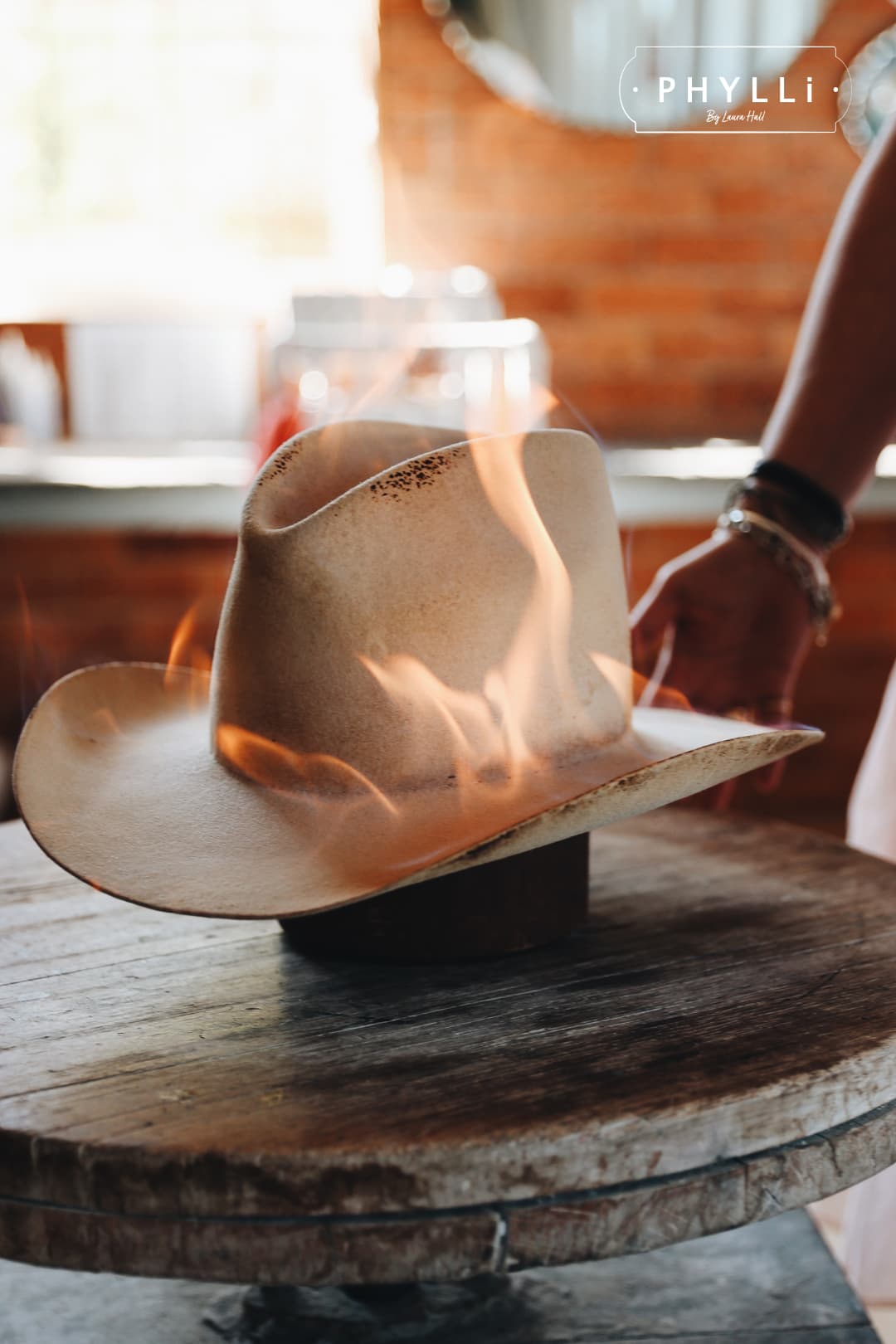 The Wheeler premium felt hat in distressed Beige being flame treated during the distressing process.