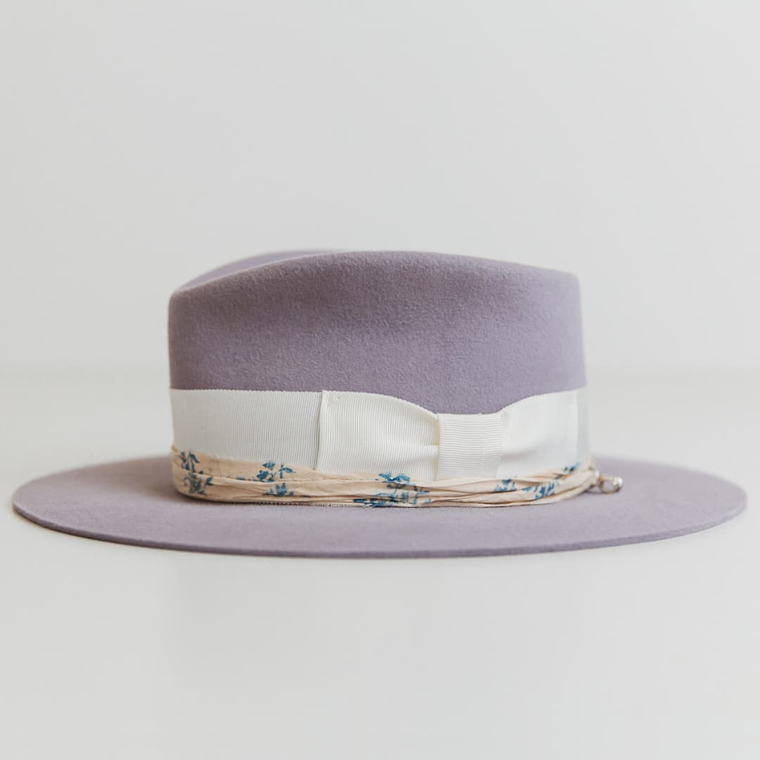 Left side view of The Wisteria lilac felt hat by PHYLLi Designs with sari silk trim and silver pendant charm.