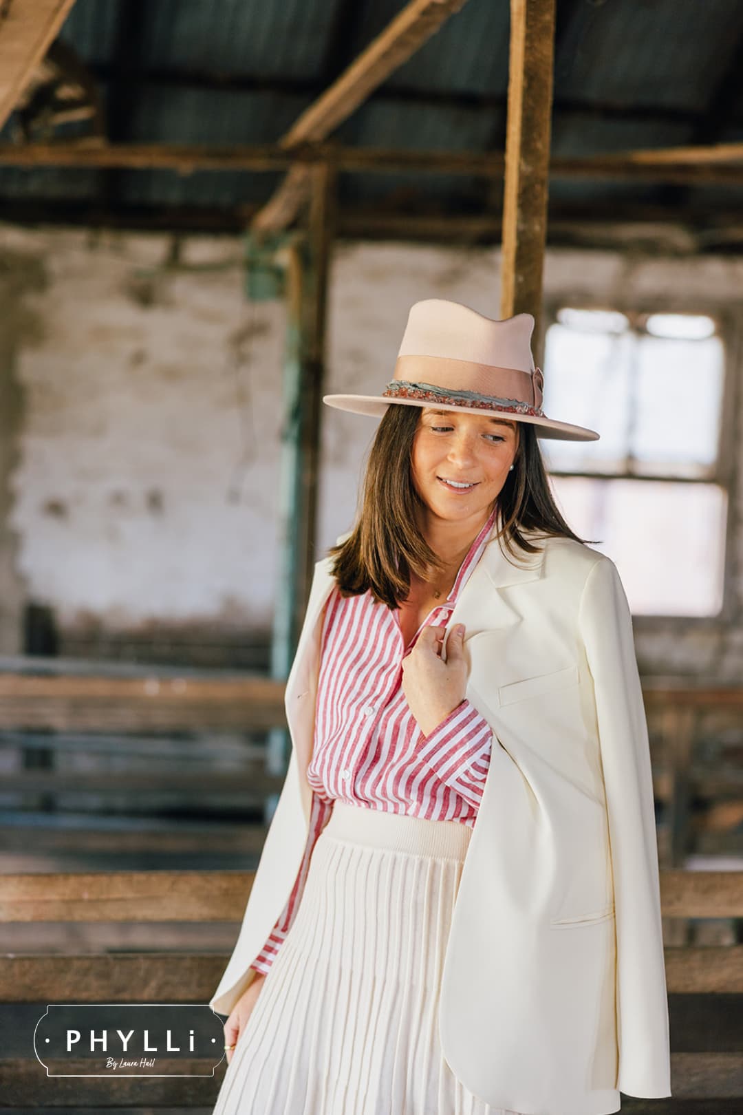 Brunette model wearing the Tourmaline Baby Pink felt hat by PHYLLi Designs with rose quartz hat necklace in a rustic shearing shed setting.