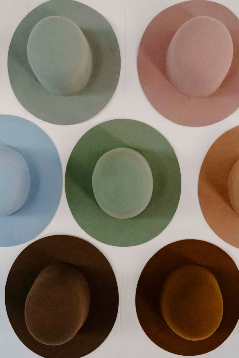 Assorted felt hat bases displayed on wall showing colour options in the PHYLLi hat studio.