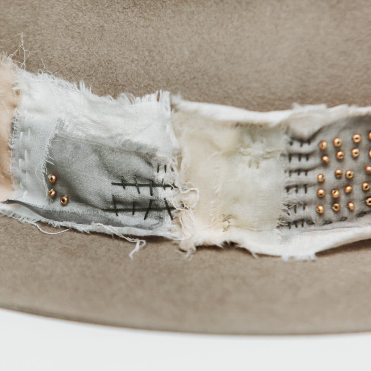 Close up detail of the Wabi Limited Edition felt hat showing matte gold bead accents and hand stitched patchwork band.