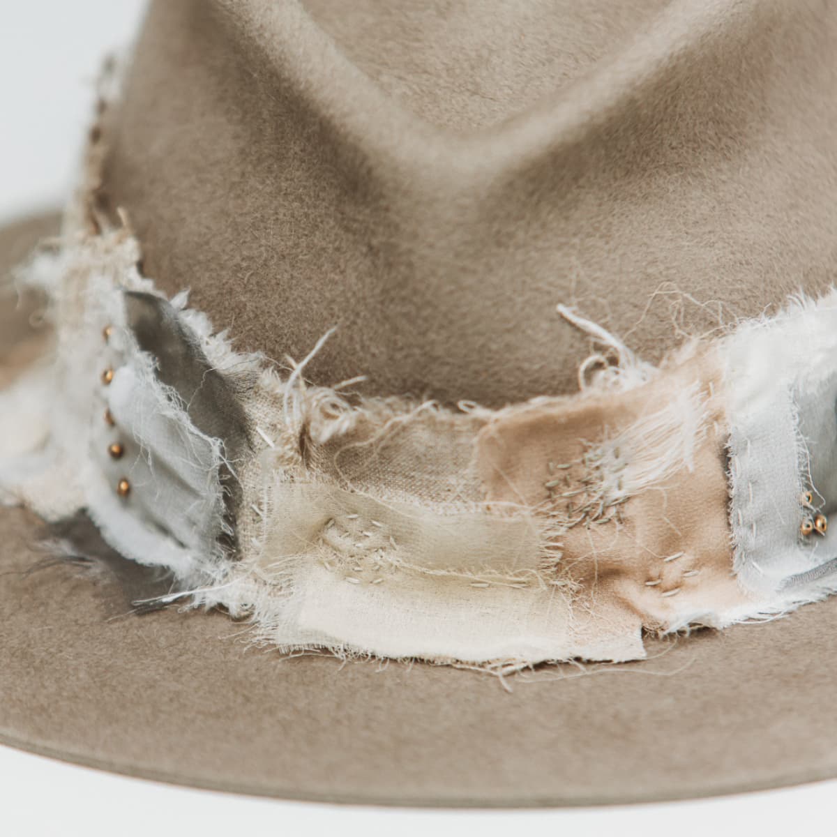 Close up detail of the Wabi Limited Edition felt hat showing sashiko stitching in Ivory, Taupe, Stone and Cement across linen and silk patches.
