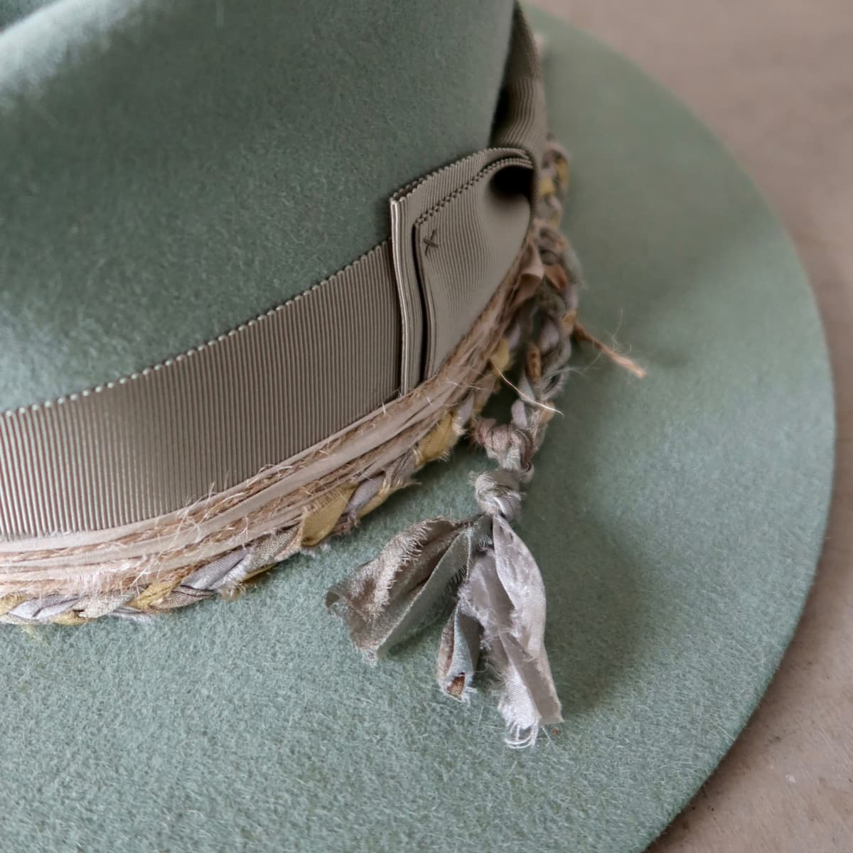 Close up detail of the Wheatley Limited Edition felt hat showing oil green Japanese grosgrain bow band with plaited sari silk trim.