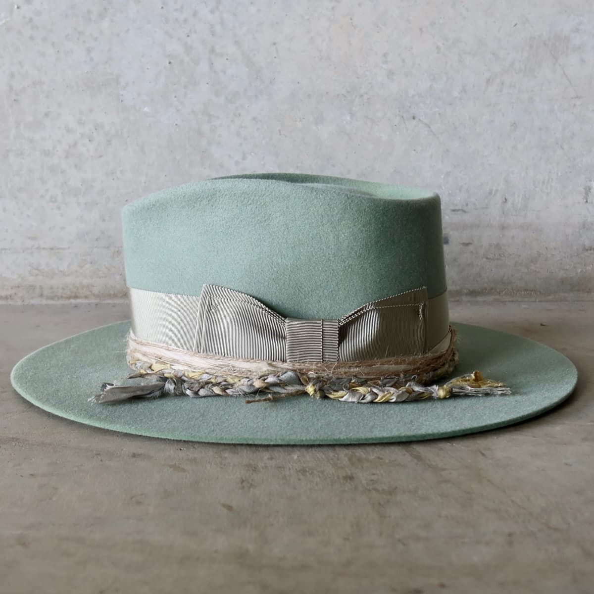 Left side view of the Eucalyptus felt hat Wheatley Limited Edition by PHYLLi Designs with plaited sari silk trim and tie dye sari silk trimming in sand and sky blue.
