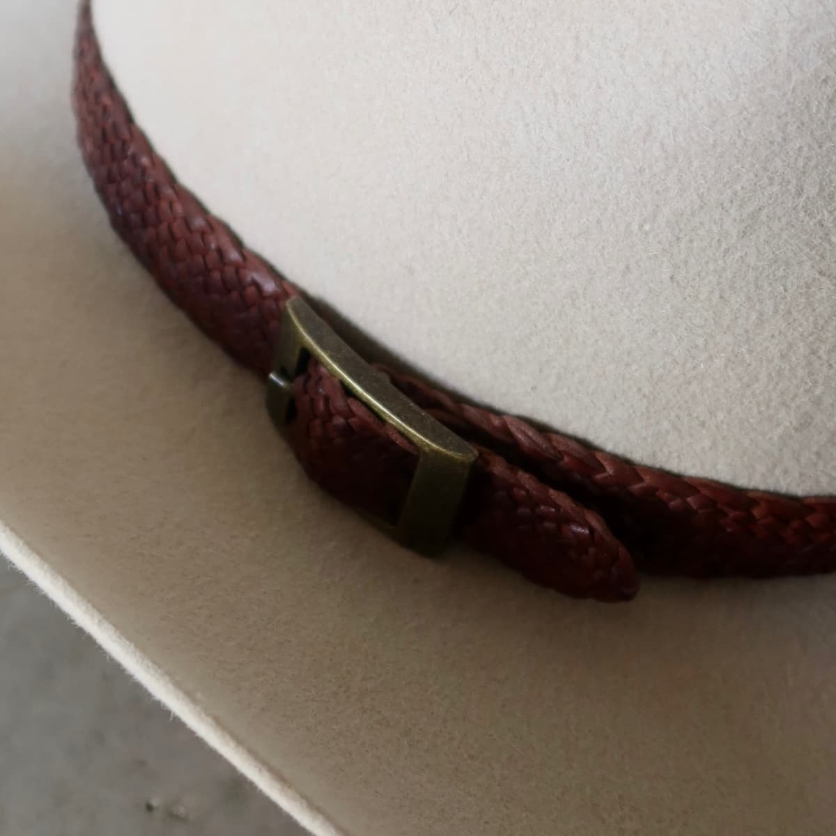 Close up detail of the Wheeler Beige cowboy hat showing 12 strand chocolate leather hat band with bronze buckle.