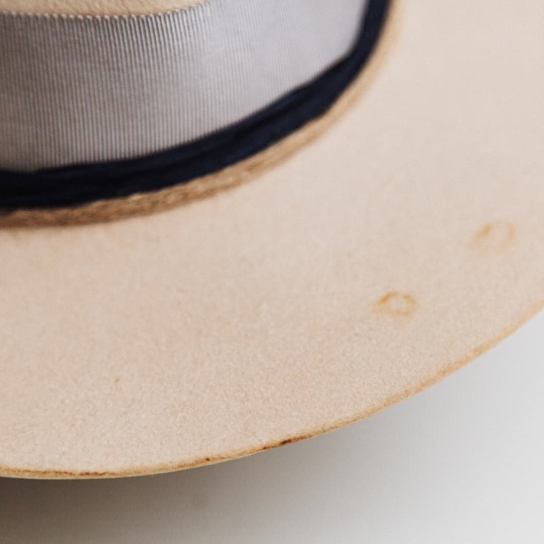 Close up detail of the Wrangler beige distressed felt hat by PHYLLi Designs showing the distressed brim with burn-aged markings and vintage wear.