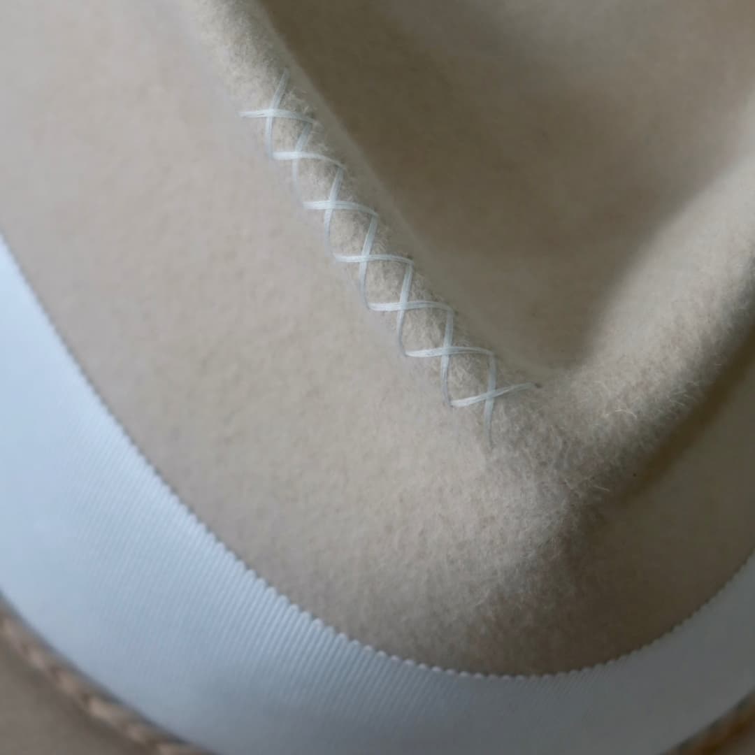 Close up detail of the Yolande felt hat showing hand-stitched cross detail in ivory.