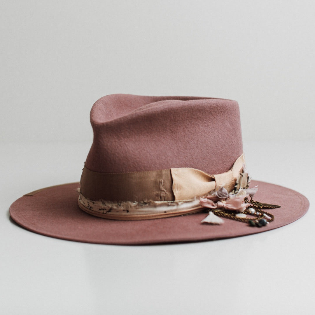 Front left angle of the Celia blush felt hat by PHYLLi Designs with distressed taupe Japanese grosgrain band, sand bow and sari silk trimming.