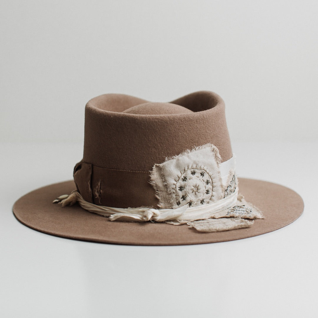 Back view of the Enso sahara felt hat by PHYLLi Designs featuring charm cluster with ivory tassel, silver charm and moonstone.
