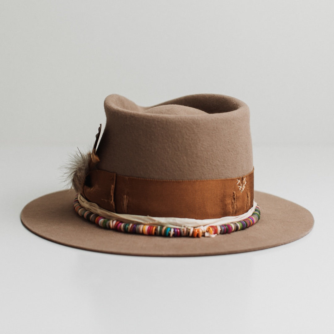 Back view of the Mango Sahara felt hat by PHYLLi Designs featuring distressed copper grosgrain band with ivory darned patches and rainbow disc hat necklace.