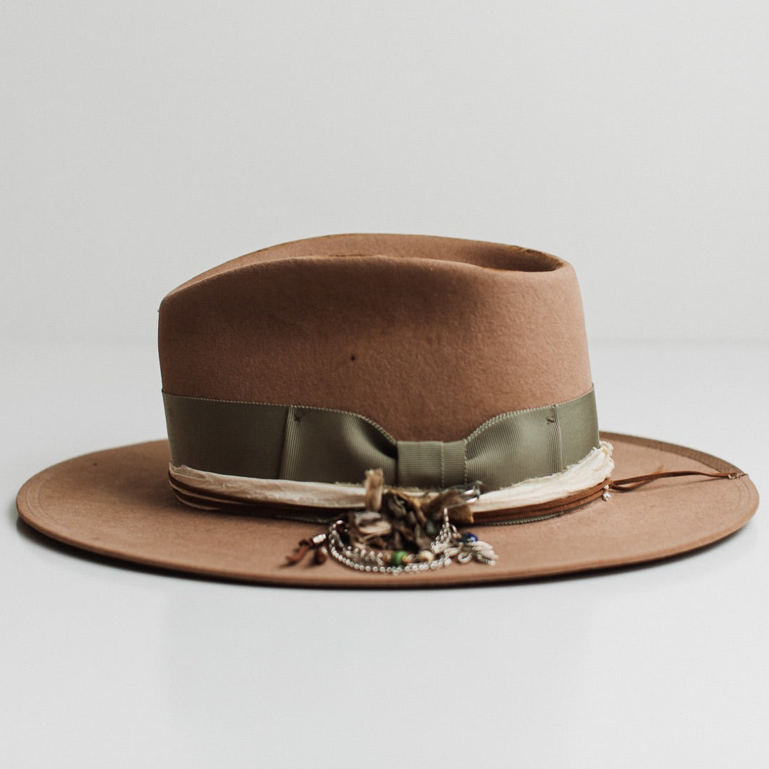 Left side view of the Nim camel distressed felt hat by PHYLLi Designs with floral and linen patches, tan suede string and layered sari silk trims.