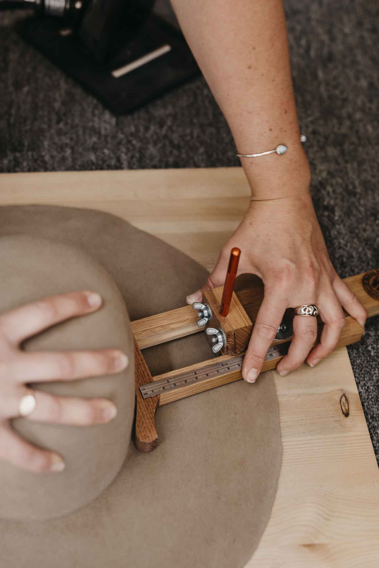 Laura Hall, Australian hatmaker, cutting the brim of a felt hat base in the PHYLLi Designs studio.