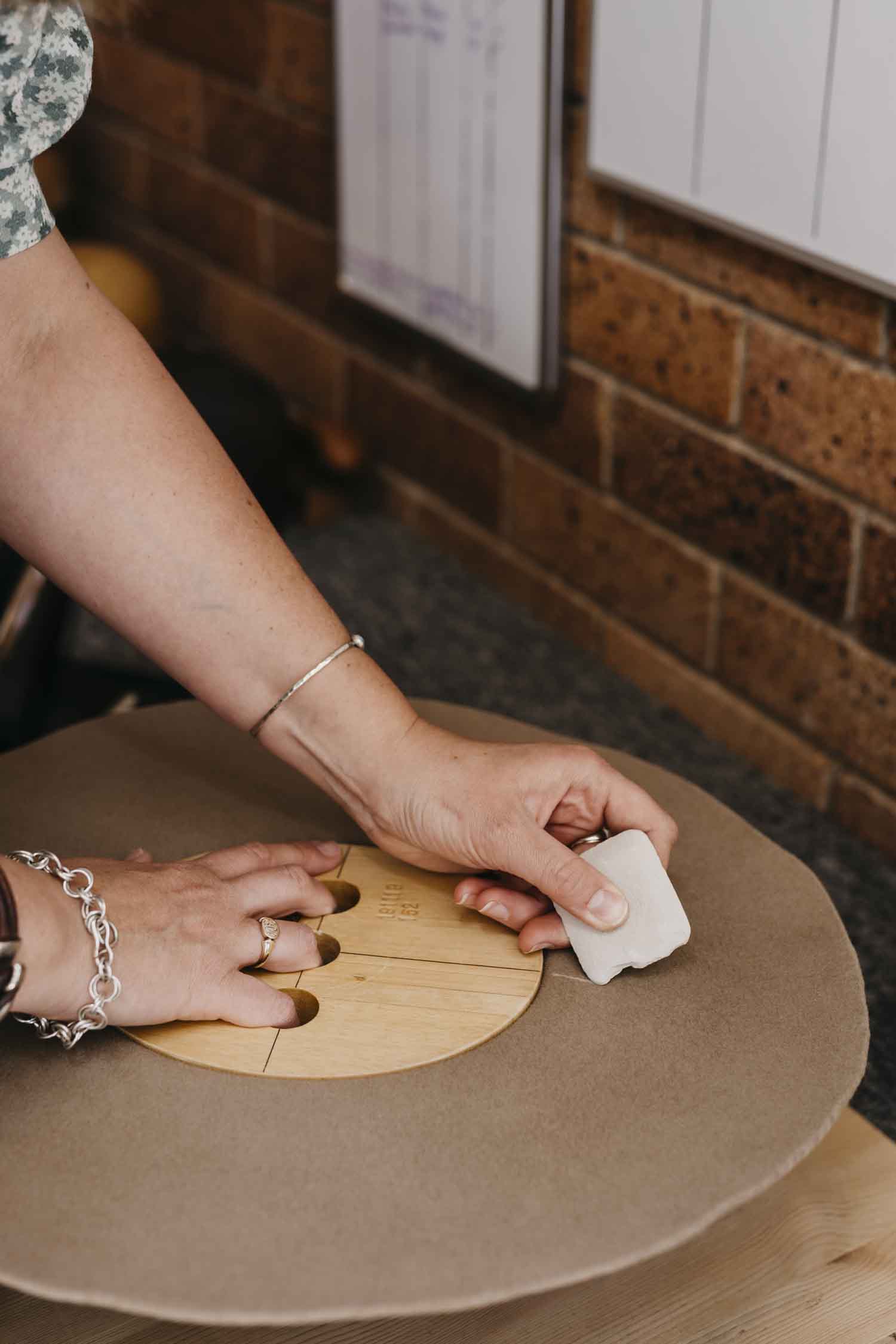 Laura Hall marking a custom felt hat with dressmaker’s chalk during production at PHYLLi Designs.