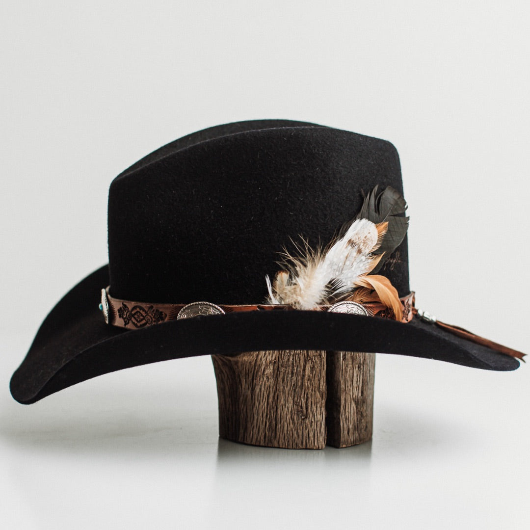 Left side view of The PHYLLi dark navy felt hat by PHYLLi Designs with feather cluster and engraved leather hat band.