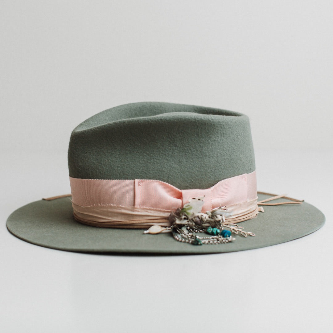 Left side view of The Sage sage felt hat by PHYLLi Designs with taupe grosgrain brim trim, nude suede string and baby pink sari silk trimming.